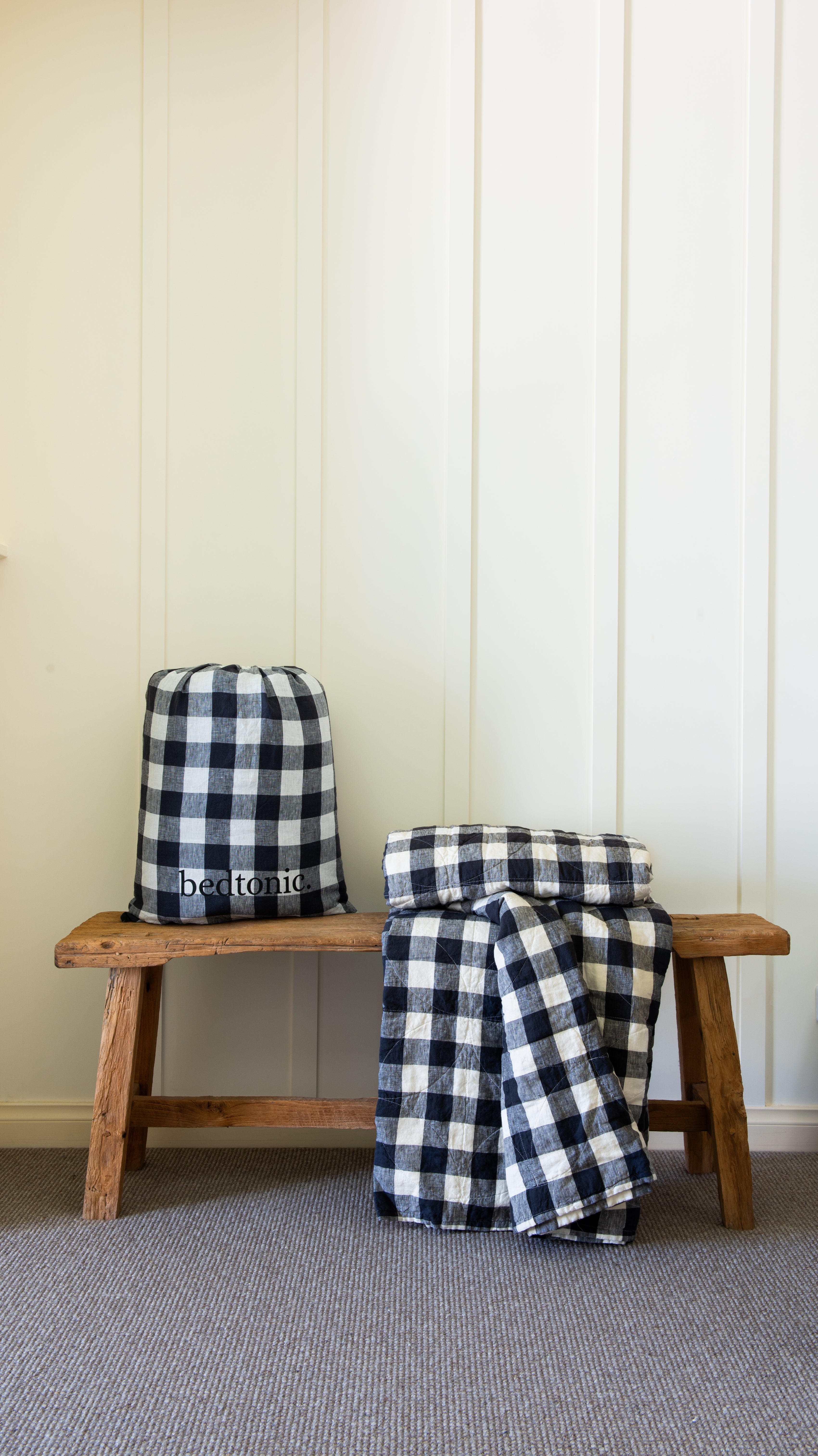 Indigo and white check linen blanket set folded on a wooden bench