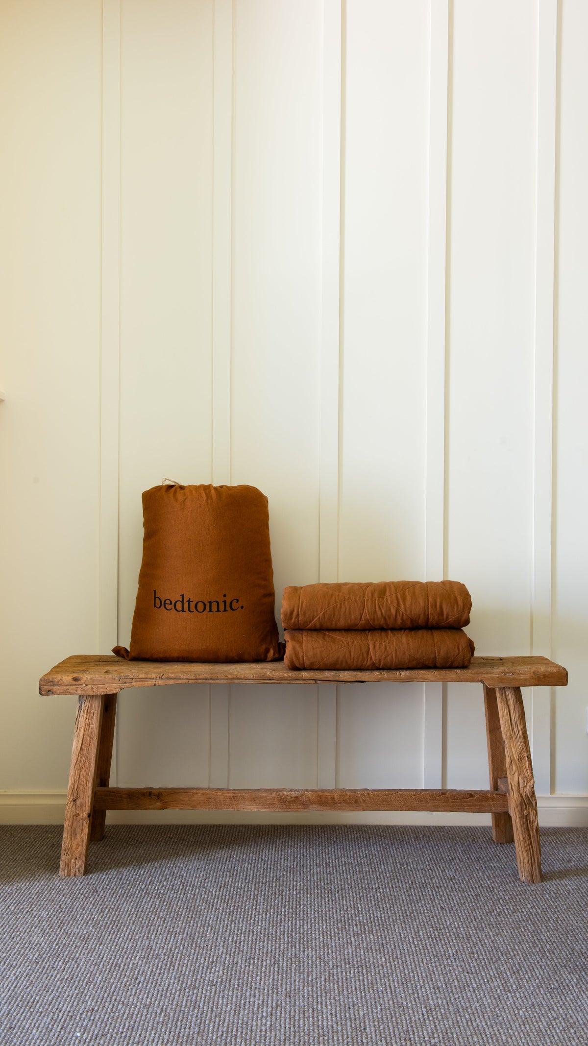 Terracotta flax linen blanket stacked on a bench with circular stitched quilting