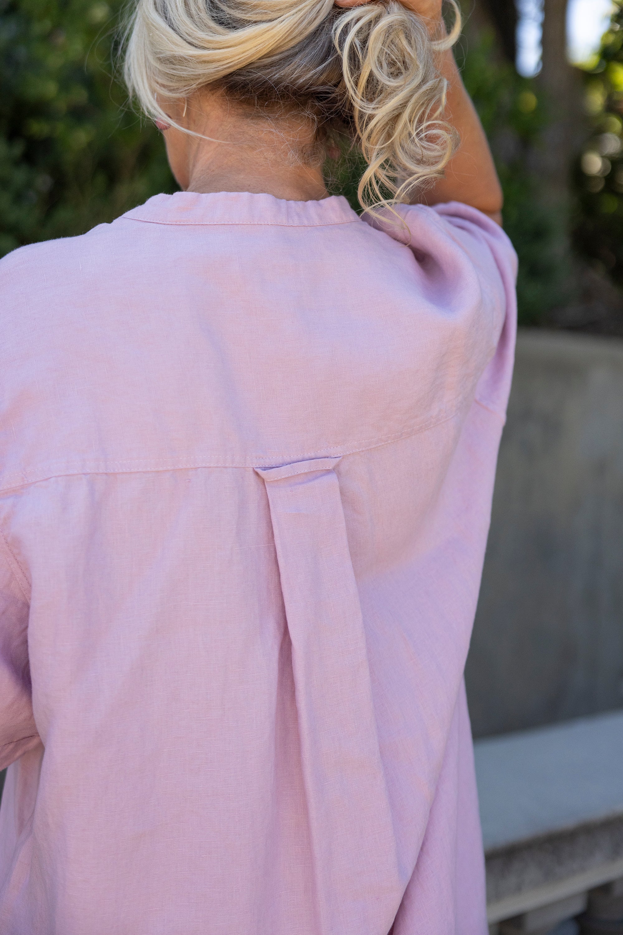 Person wearing a light pink shirt with a blurred background