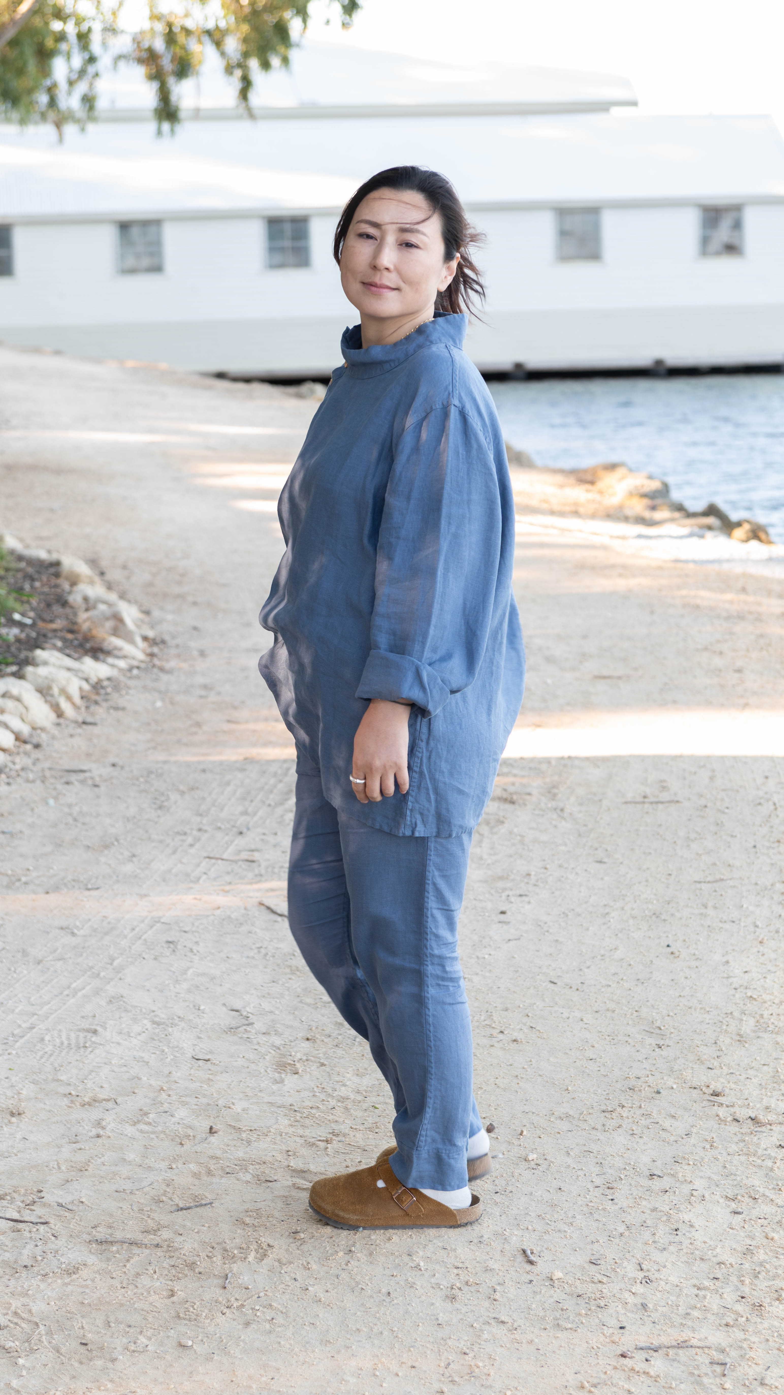Woman in a denim blue tunic and matching trousers in front of a lake