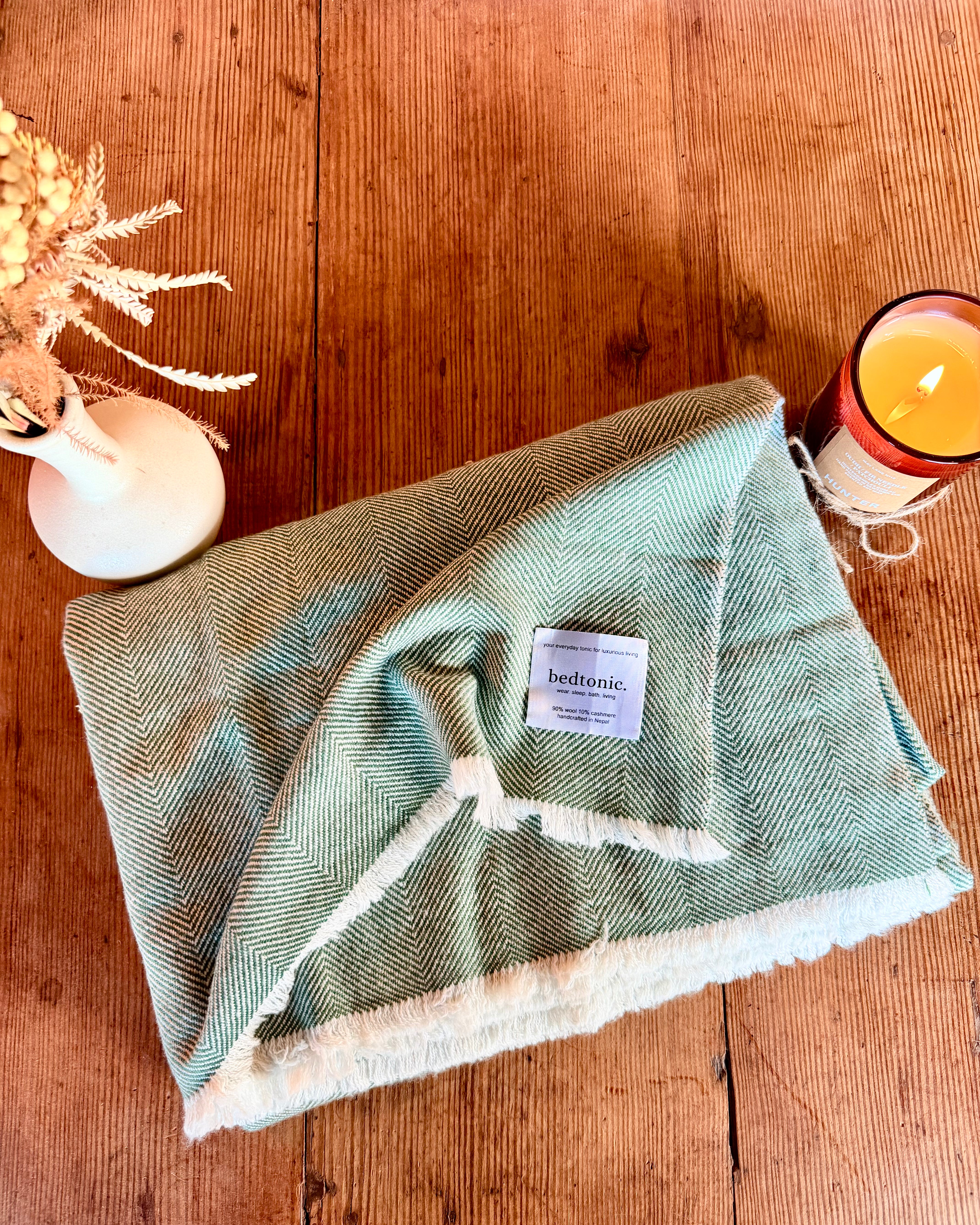 Moss green wool-cashmere throw with chevron weave, fringed border, brand label visible
