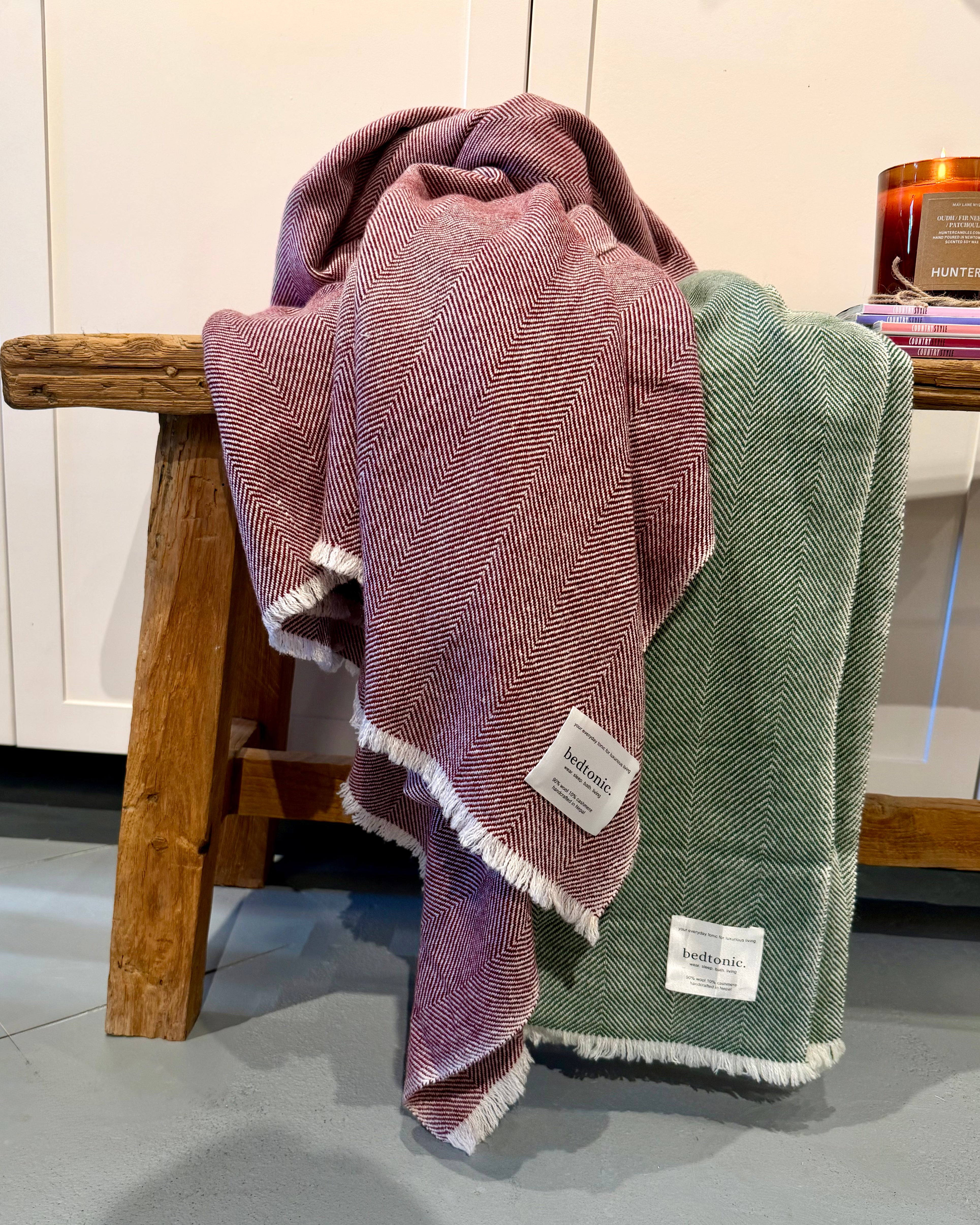 Mauve throw with chevron pattern and fringed edge, paired with teal throw on bench
