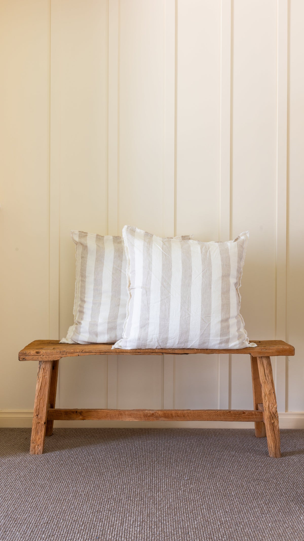 Vertical striped linen pillowcases on bench, natural tones, hand-frayed edges