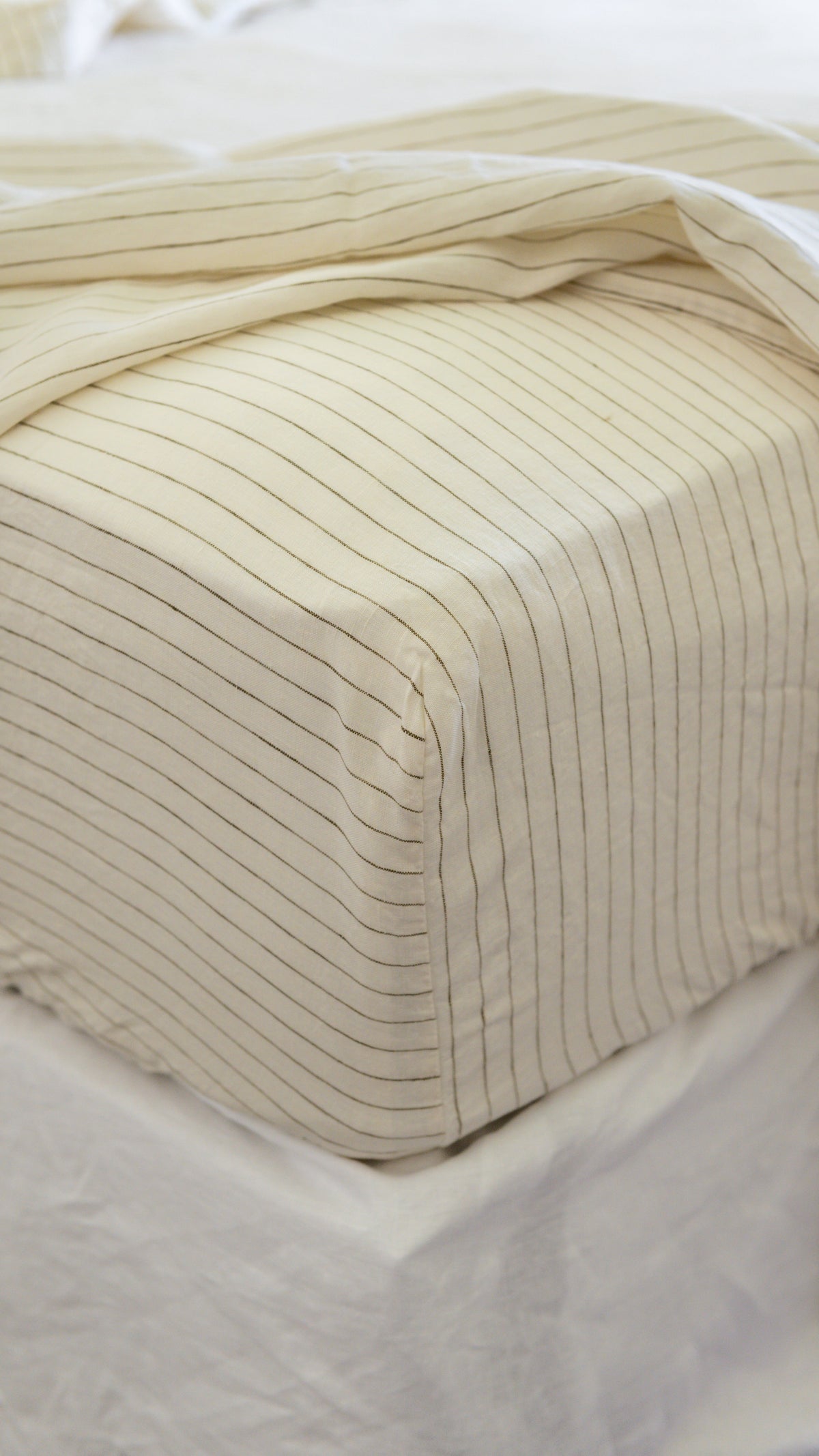 Cream fitted sheet with thin olive pinstripes and fitted corner