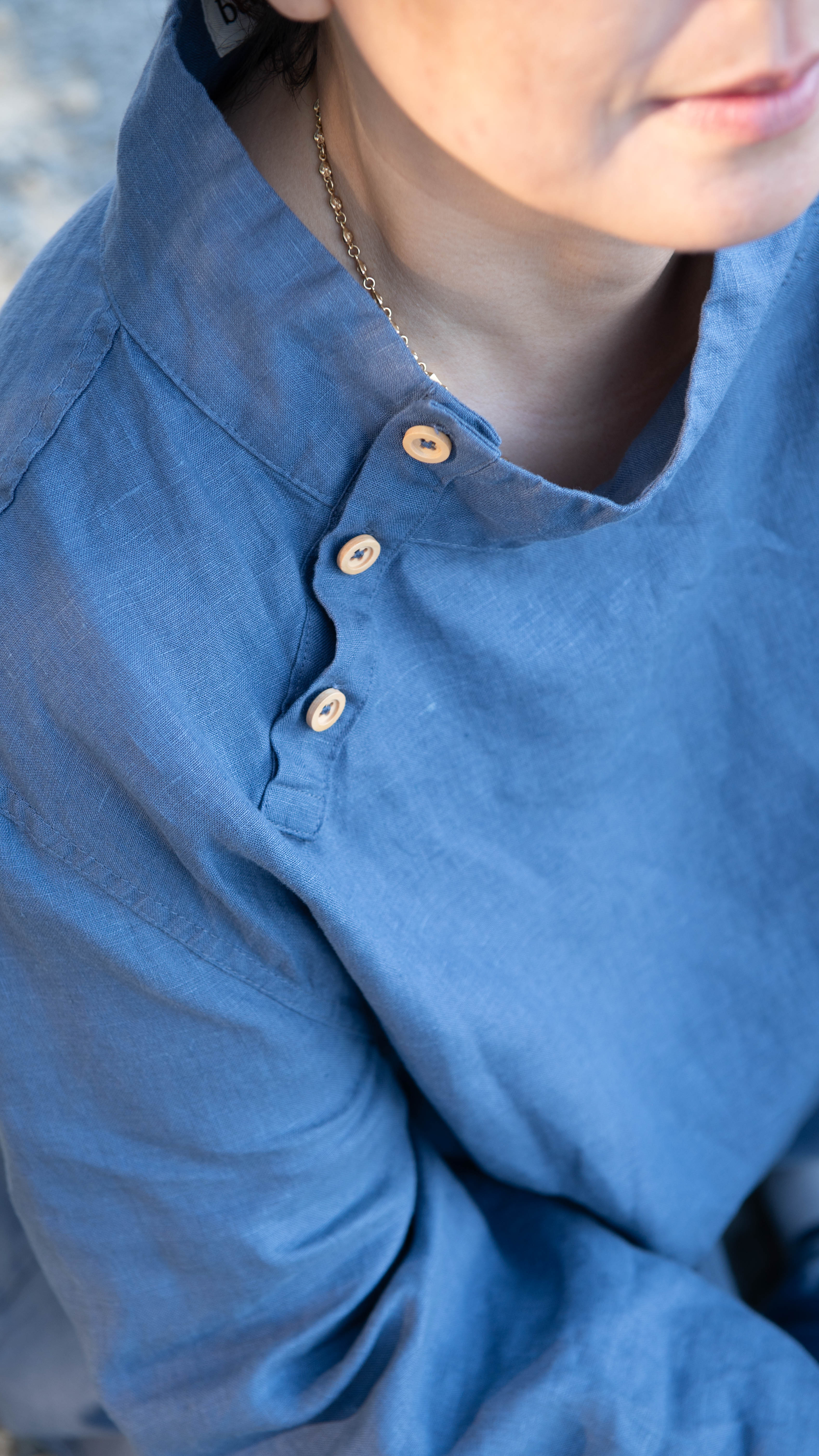 Close up of a person wearing a denim blue button up tunic