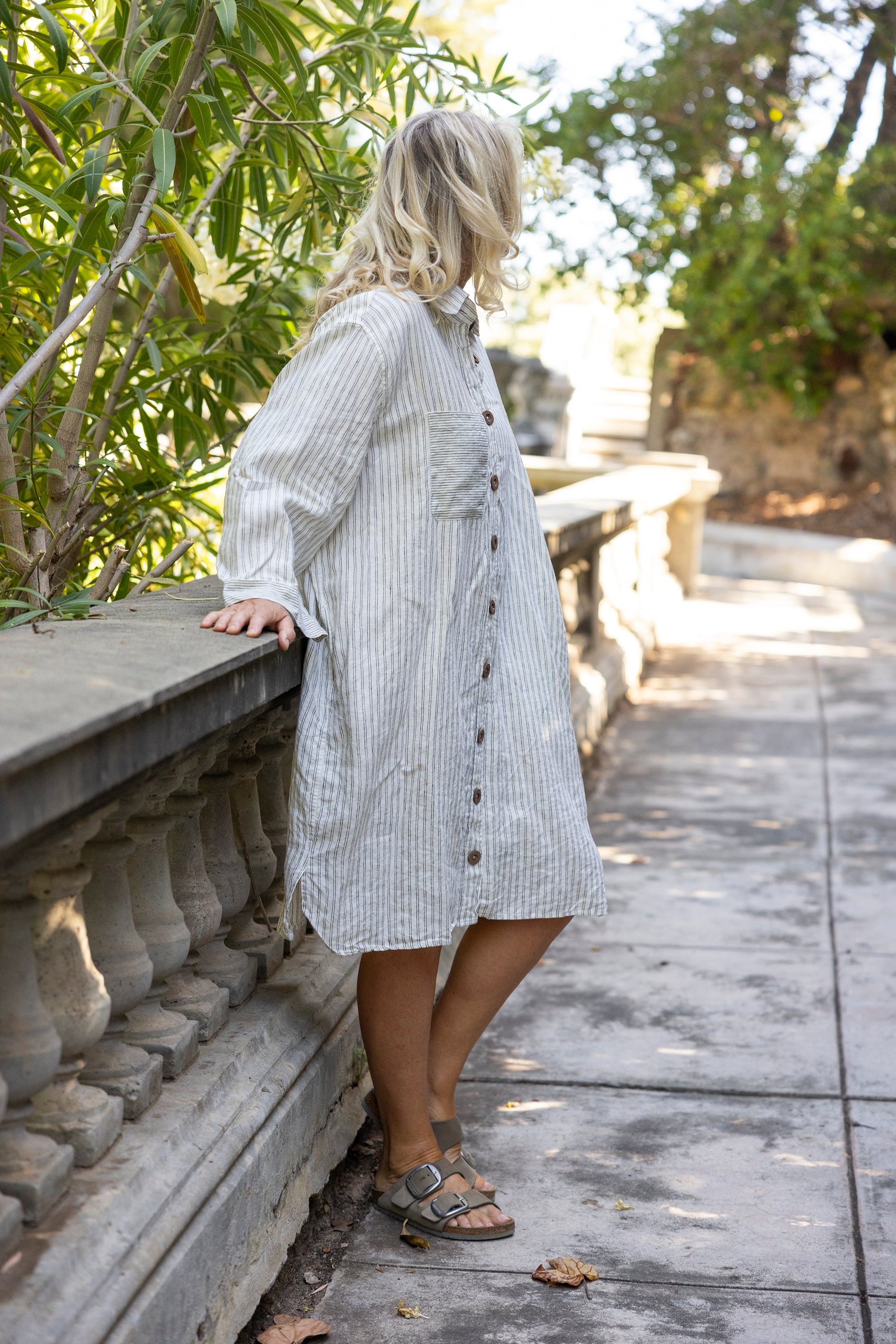 Woman in a striped dress standing on a stone path with greenery around