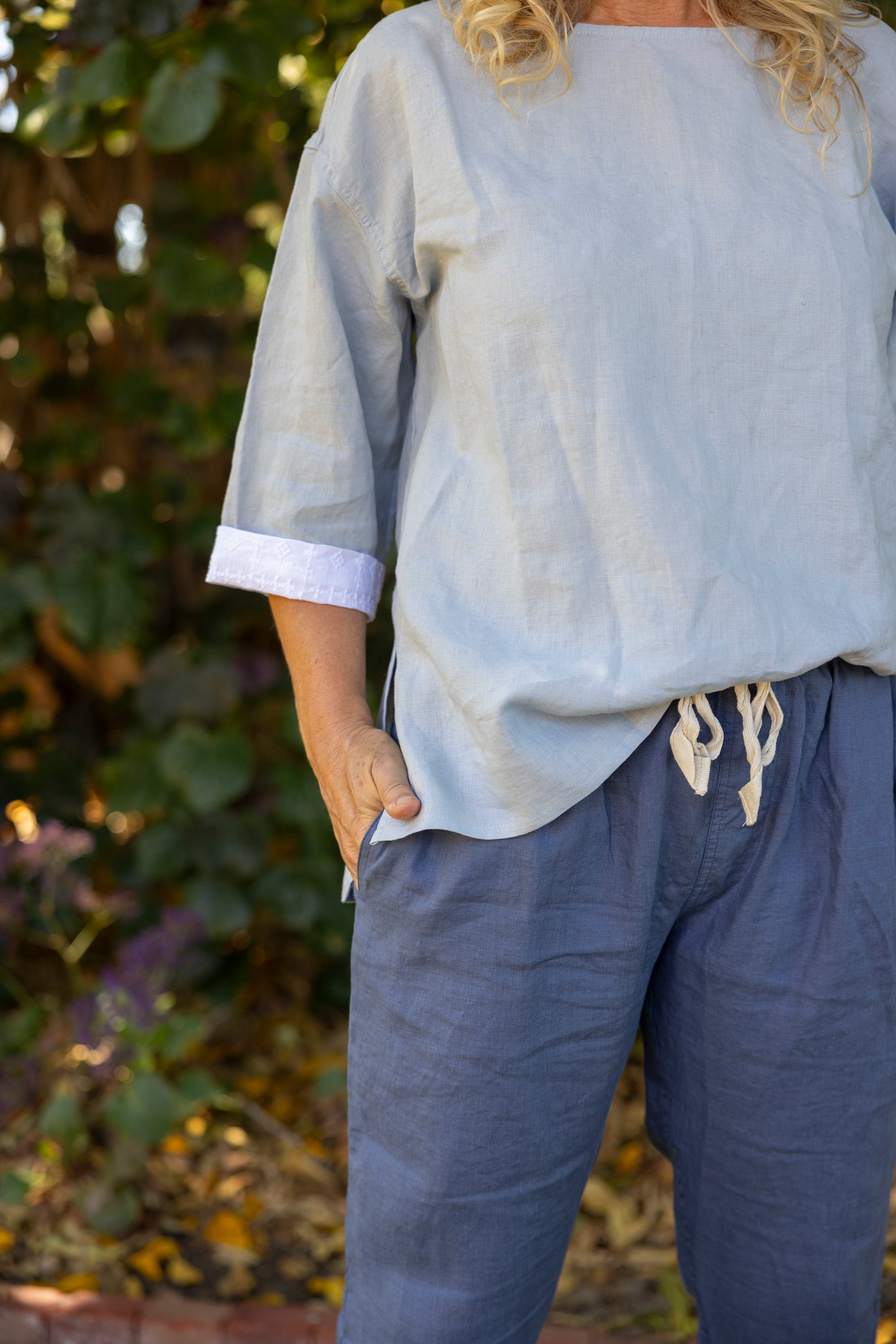Person wearing a light blue shirt and dark blue pants with a blurred natural background