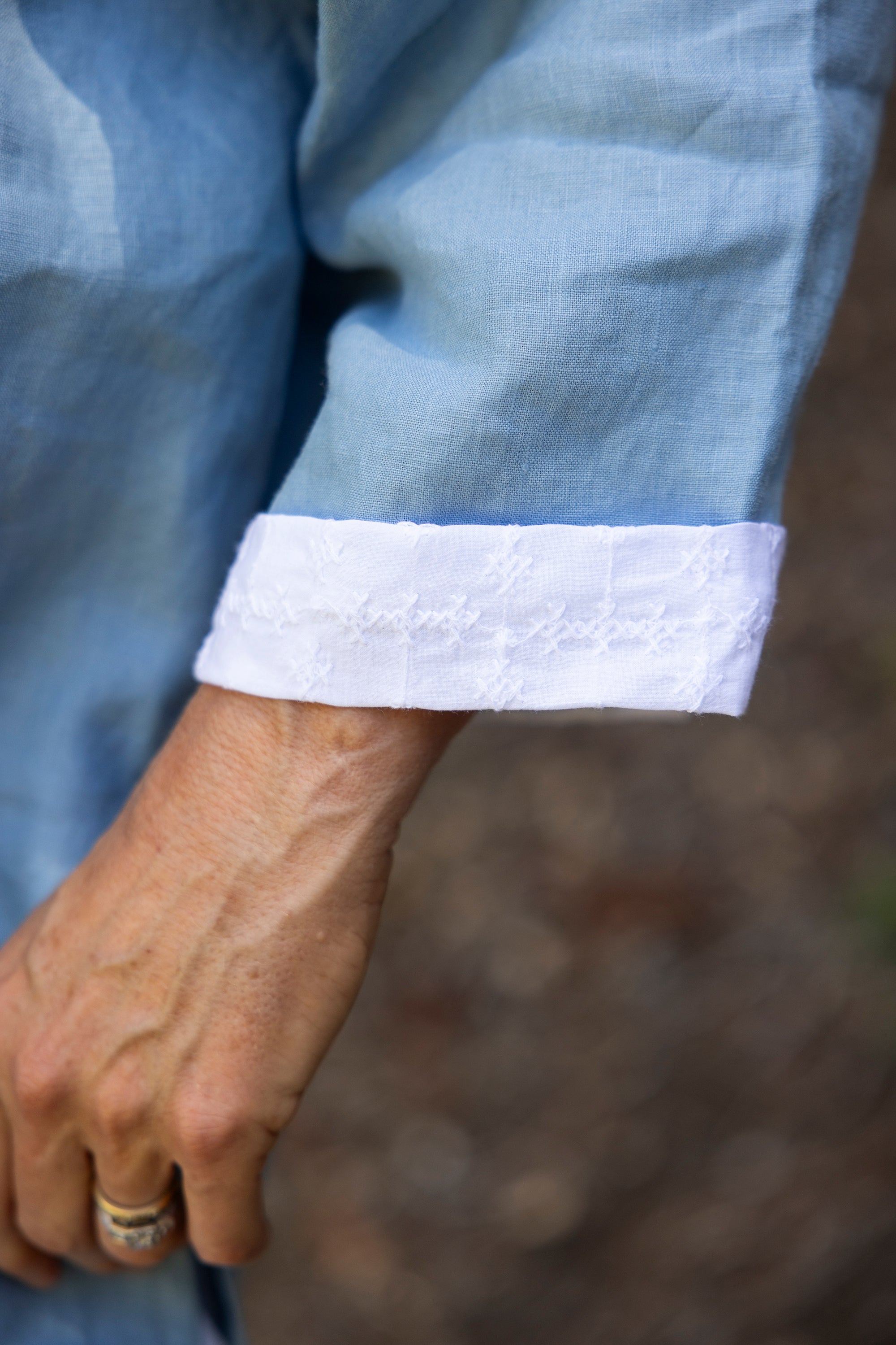 Close-up of a light blue shirt with white cuffs and a blurred background