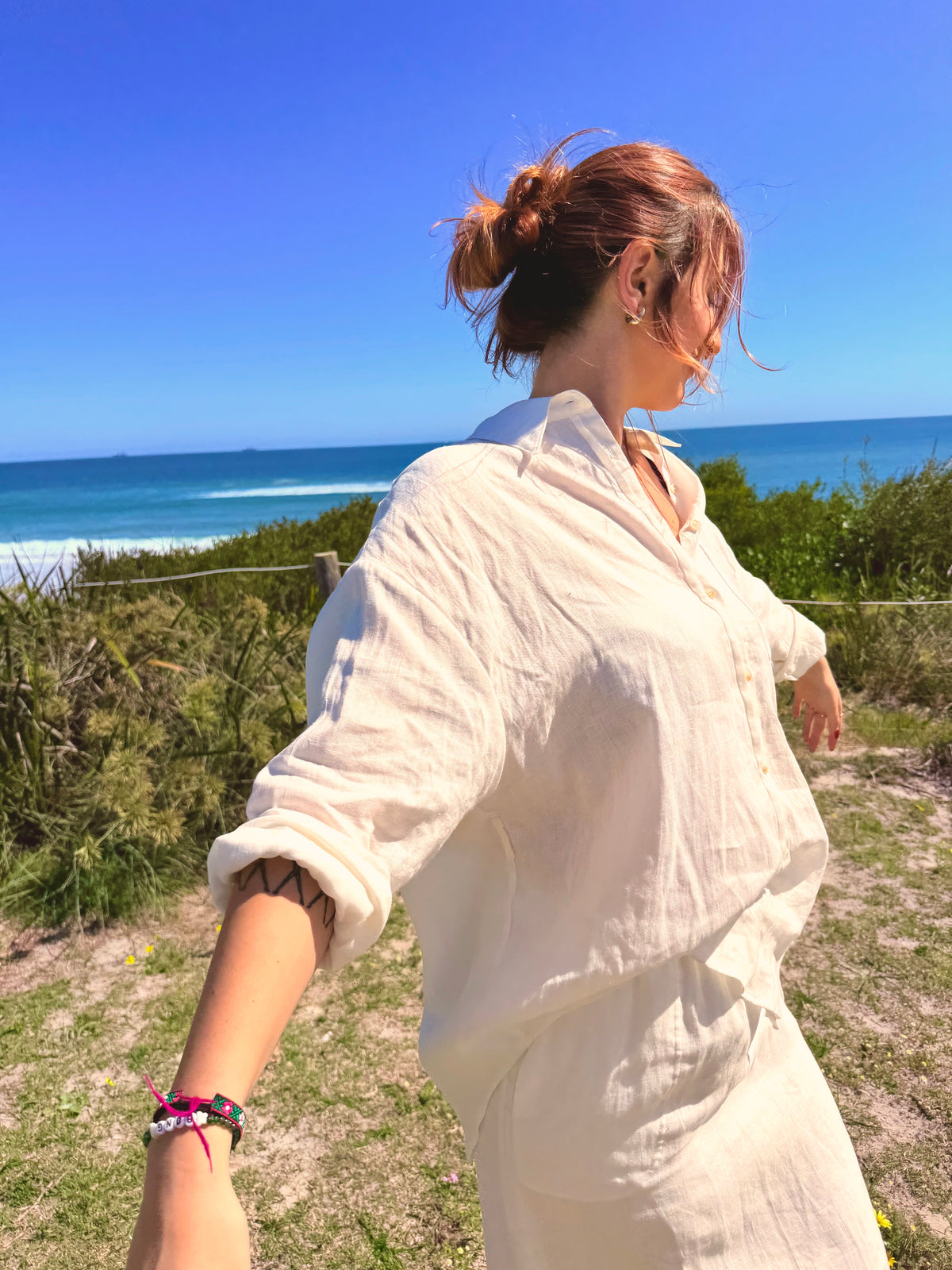 White linen button-front tunic with rolled sleeves and tie waist, paired with long skirt