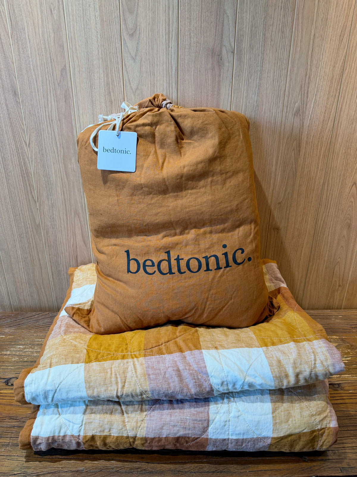 Flax linen blanket with terracotta-brown fabric and pale blue check border, folded