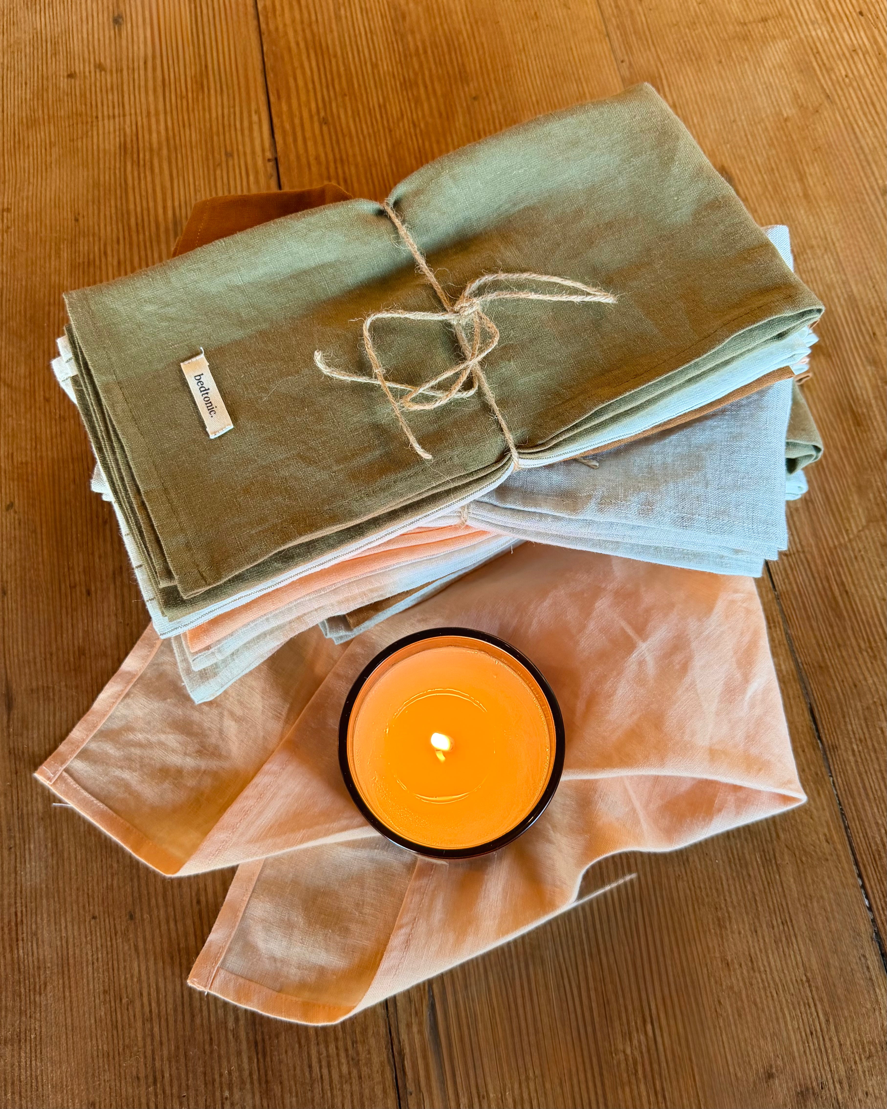 Linen tea towel set stack in olive green, light blue, and peach with tied tags
