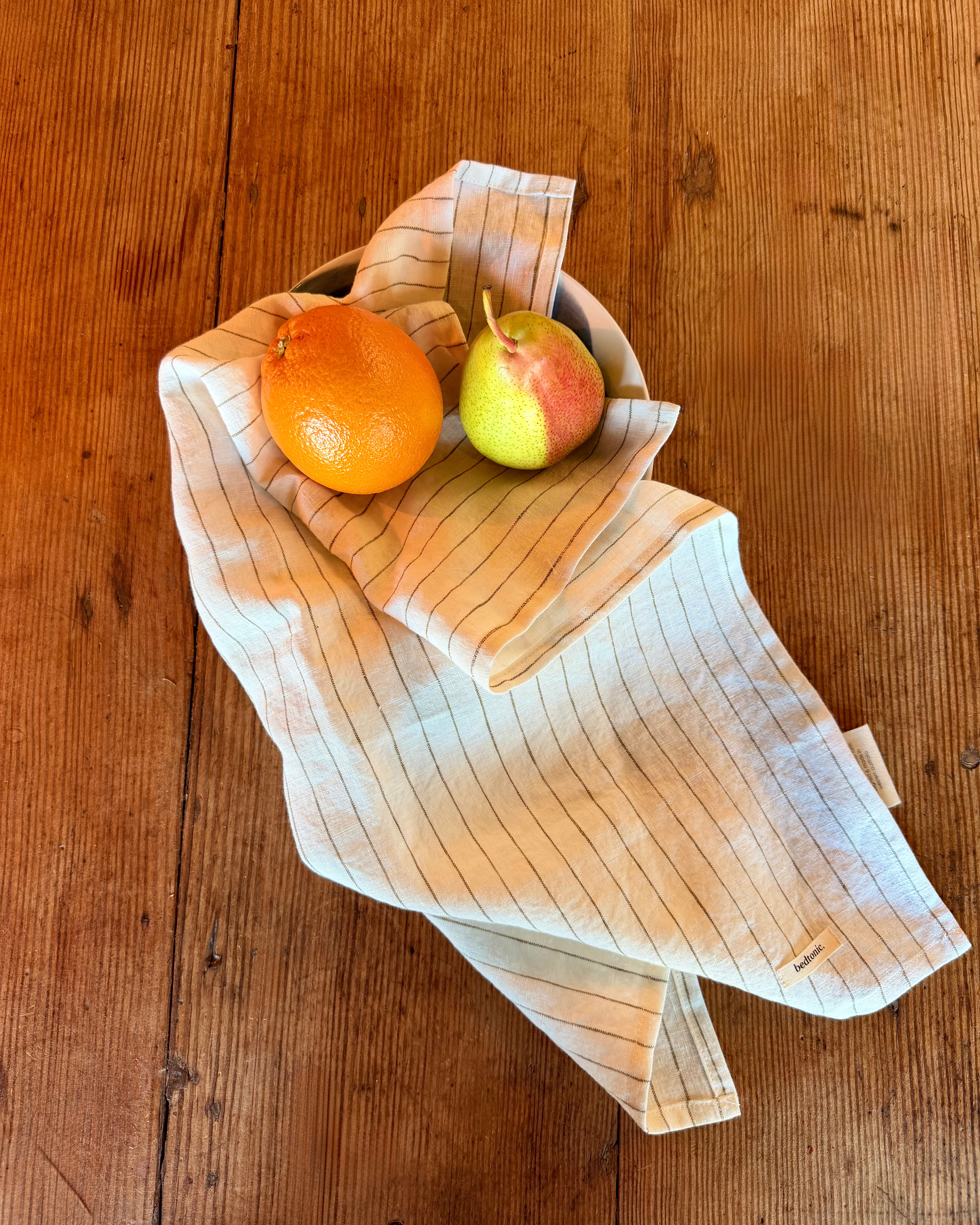 Linen tea towel set in natural off-white with thin vertical stripes and fruit props