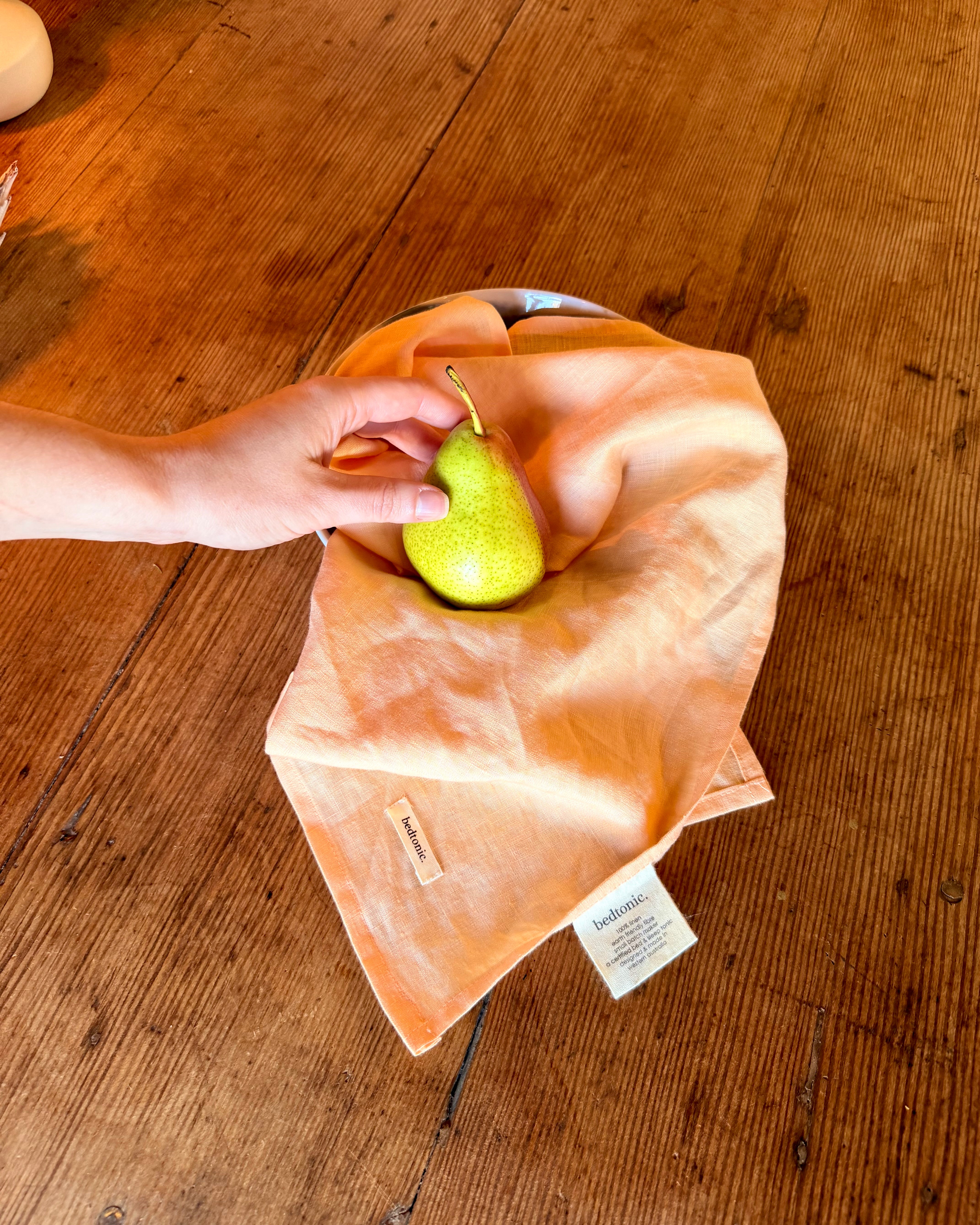 Linen tea towel set in peach with small woven label on folded towel